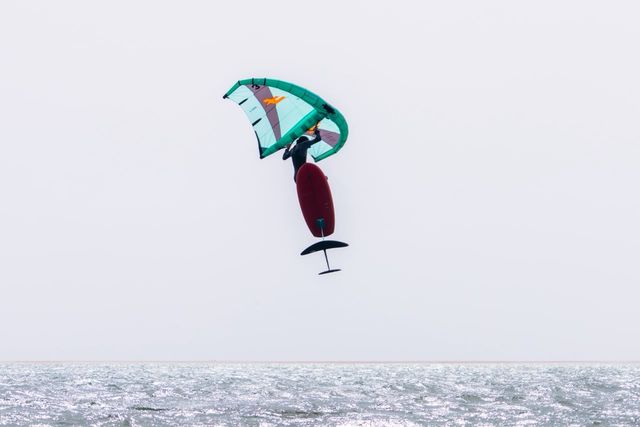 Abdou jumping with his wing and foil board above the lagoon